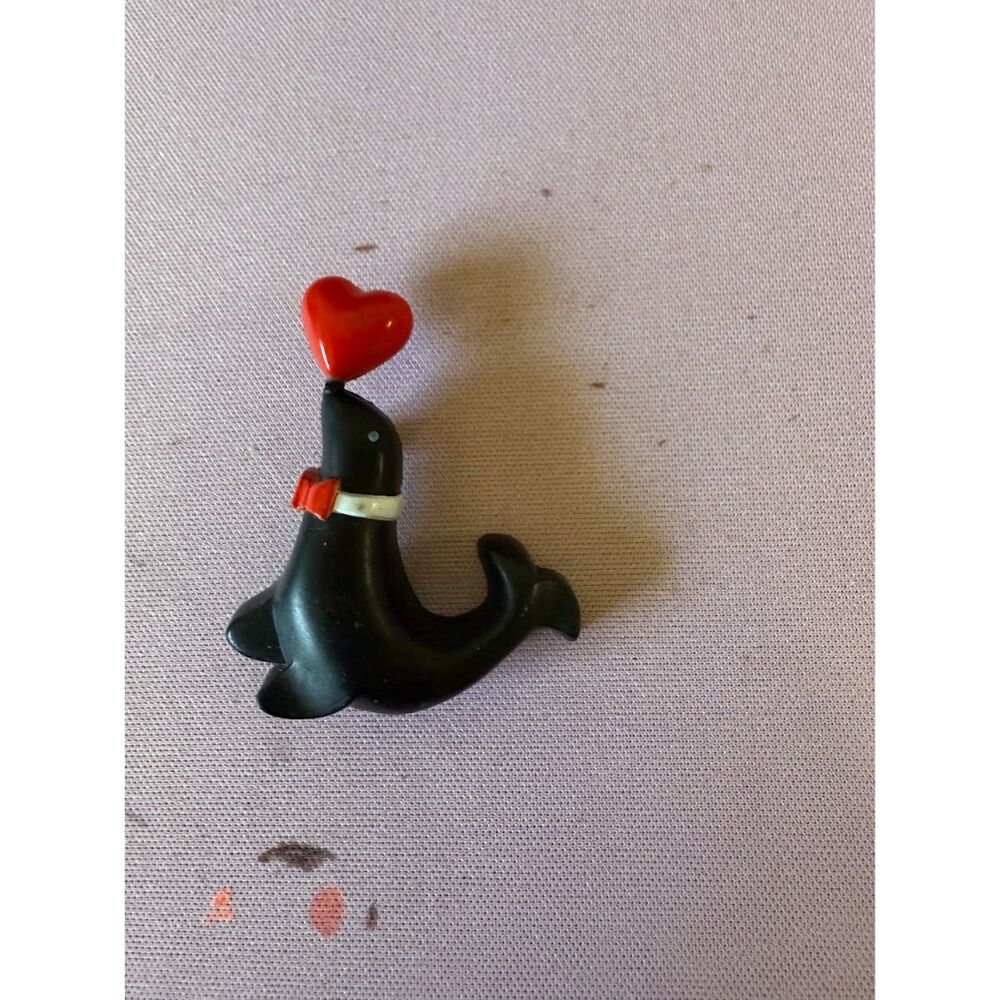 vintage Valentine pin featuring a black seal balancing a red heart on its nose